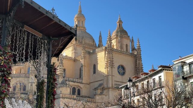 Static shot detailing the ornate Gothic architecture of the Segovia Cathedral accented by festive holiday decor on a bright sunny winter day in Segovia, Spain.