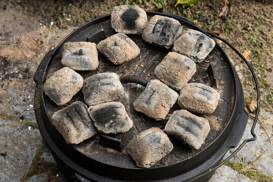 Close-up of cast Iron Dutch Oven with burning charcoal  briquettes for top heat.