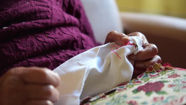 M&atilde;os de mulher idosa fazendo bordado &agrave; m&atilde;o, artesanato tradicional e atividade de coordena&ccedil;&atilde;o motora