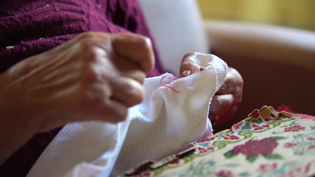 M&atilde;os de mulher idosa fazendo bordado &agrave; m&atilde;o, artesanato tradicional e atividade de coordena&ccedil;&atilde;o motora