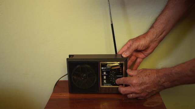 Pessoa idosa sintonizando r&aacute;dio antigo em casa simples, cena nost&aacute;lgica da vida no interior do Brasil