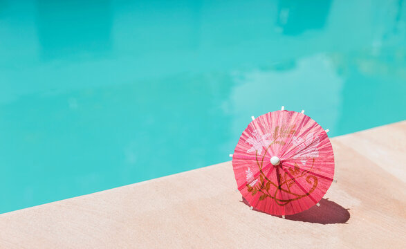 Red paper umbrella on swimming pool edge, summer season background