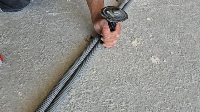 Top-down slow-motion footage detailing the hammer strike as the nail-in anchor clamp secures the electrical conduit pipe to the floor.