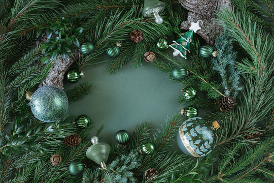 Overhead view of a festive Christmas background framed with evergreen branches, pinecones and assorted Christmas baubles and ornaments