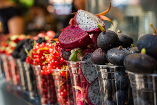 Close-up of a row of plastic cups filled with assorted fruit at a street market