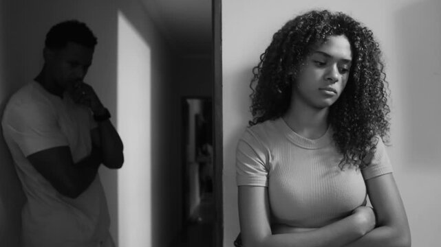 Teenage daughter and father in monochromatic scene standing apart, arms crossed, expressing emotional distance, tension, and unresolved conflict in family relationship