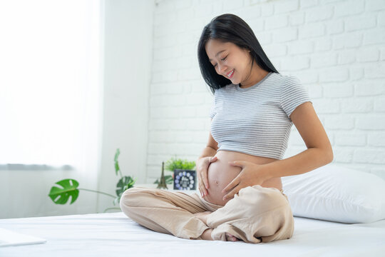 Image of a beautiful Asian pregnant woman in bed at home.