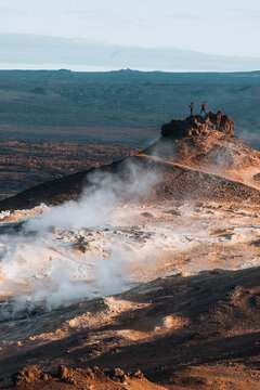 Hikers standing above steaming geothermal field