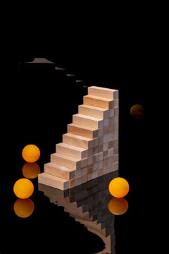 Pyramid of wooden blocks with orange balls on a black background