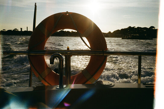 Orange life buoy on boat stern at golden hour