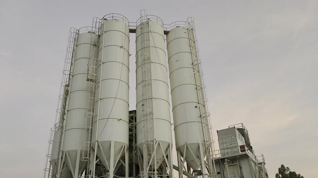 A cluster of tall steel silos storing cement or fly ash for continuous concrete batching operations.