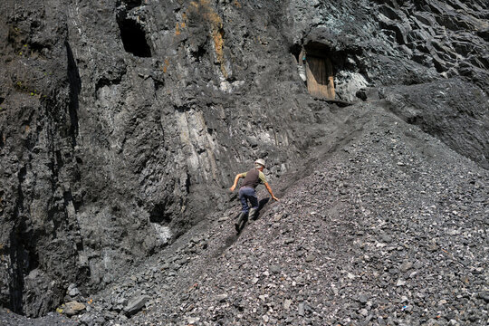 Miner climbing steep mountain slope towards mine entrance