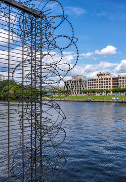 Sicherheitszaun mit aufgesetztem , spiralf&ouml;rmigem NATO-Stacheldraht am Ufer der Spree gegen&uuml;ber der M&uuml;hlenstra&szlig;e, Berlin, Deutschland