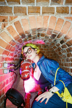 Person Poses With Red Horse Statue in Brick Tunnel at Night