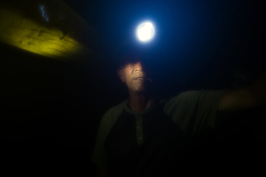 Miner working underground with headlamp illuminating darkness