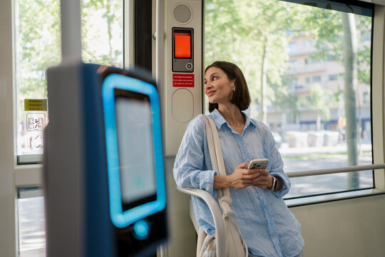 Woman inside a tram using a smartphone and looking out the window