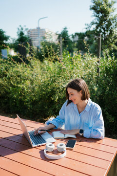 A woman uses a laptop to work at the city park