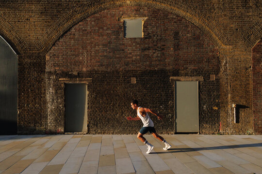 Young man running training in urban brick setting