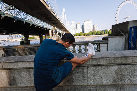 Man stretching preparing for run along London river