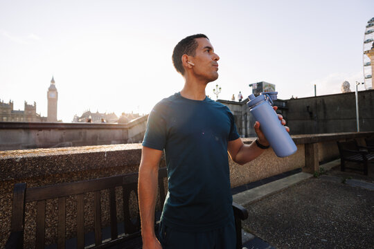 Runner hydrating after workout overlooking London cityscape