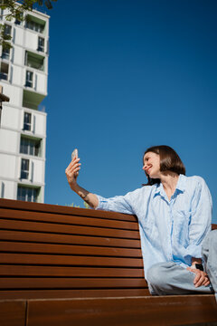 A woman sitting on a bench and making a call with a smartphone
