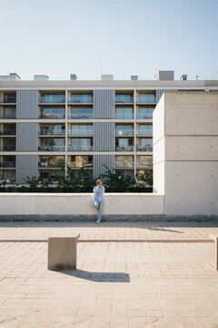 Woman Talking on Smartphone While Leaning Against Wall in the City