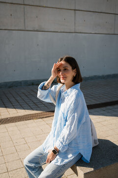 Woman Relaxing on Concrete Bench in Sunlit City with Copy Space