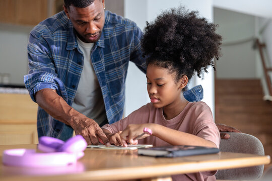 Father helping his daughter with her schoolwork at home