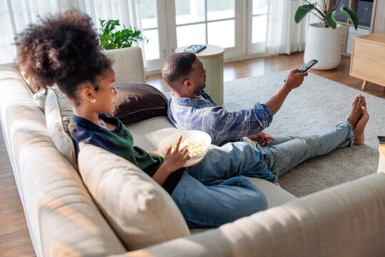 Father and daughter enjoying popcorn while watching television