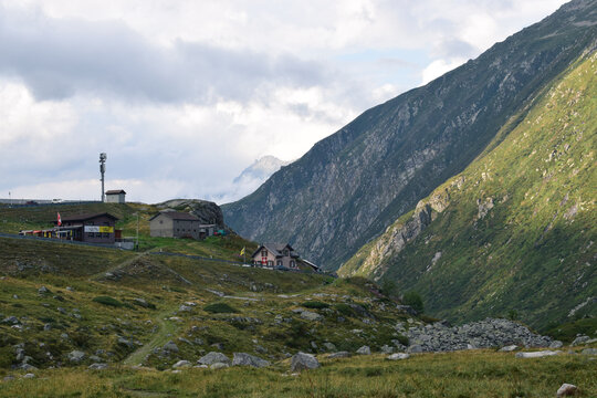 A scenic view of a mountain valley, showcasing traditional mountain refuge buildings nestled into the rugged terrain in Swiss Alps.