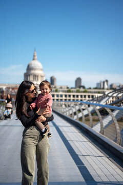 Mother Carrying Baby Across Millennium Bridge In London