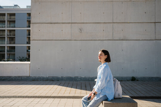 Serene Woman Enjoying Sunshine on a Bench Outdoors