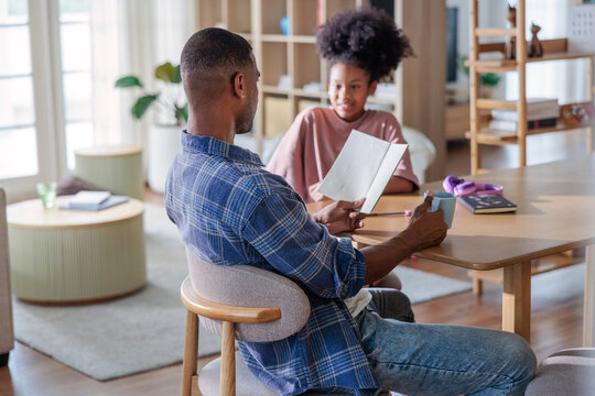 Father and daughter bonding while reading together at home.