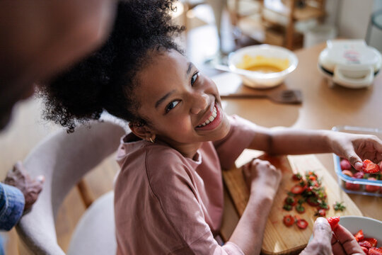 Cheerful girl smiling while preparing strawberries in the kitchen