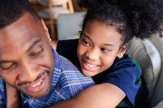 A smiling daughter affectionately hugging her father