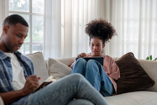 Father and daughter relaxing on a sofa at home