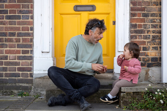 Father Feeding Baby During Snack Break Outside London House