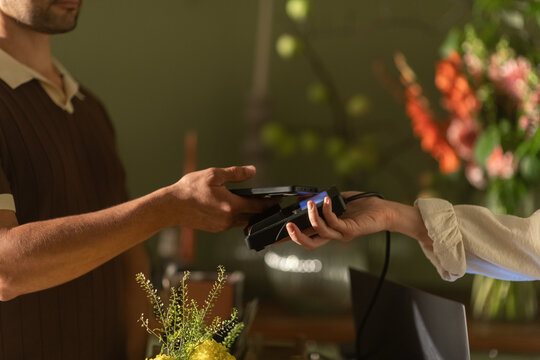 Entrepreneur holds POS terminal client pays with phone in the store