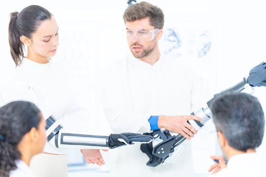 Machine learning robotics lab: researchers lower a complete robotic arm onto the bench, ready to record the next batch of motion data from its shoulder and elbow
