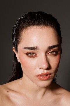Model With Wet Hair Poses Against a Dark Background