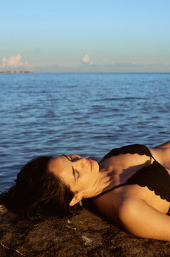 Woman relaxes by the water at sunset