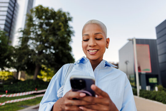 Woman smiling while using phone in city