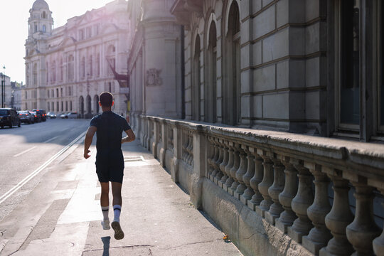 Young man running on city street by classic building
