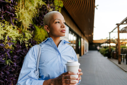 Young woman confidently walking with coffee cup