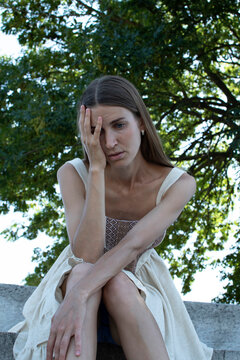A sad woman is sitting under a tree