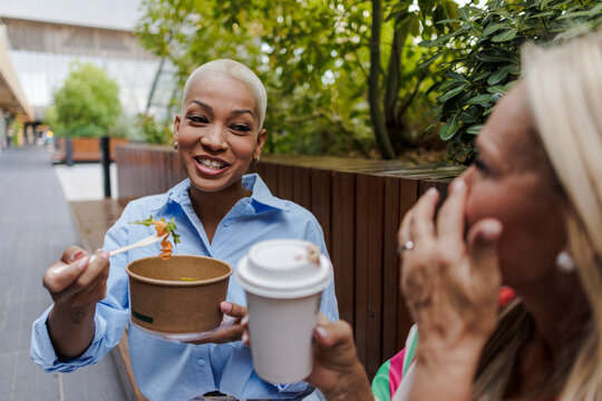 Diverse women friends sharing takeaway lunch outdoors