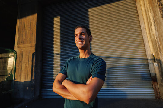 Young athlete smiling with arms crossed at sunset