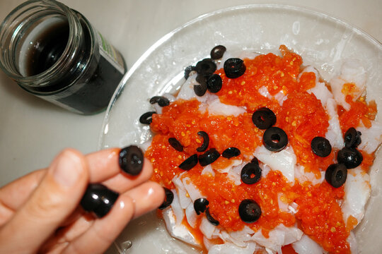 Preparing food. Cod with tomato and olives. Direct flash