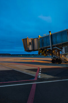 Airport jet bridge waiting on the runway apron under twilight blue sky