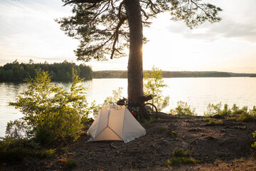 Camping tent and bicycle by tree next to lake © FOLIO